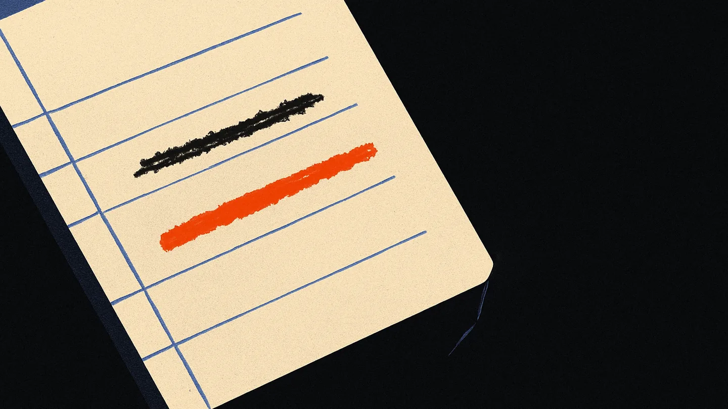 A notebook page on a dark desk with one line struck through and corrected in ember-orange ink.