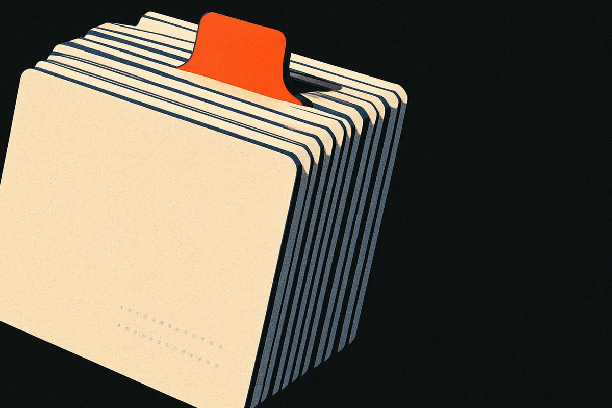 A fanned stack of index cards in the dark, one card's tab standing up above the rest, glowing orange.