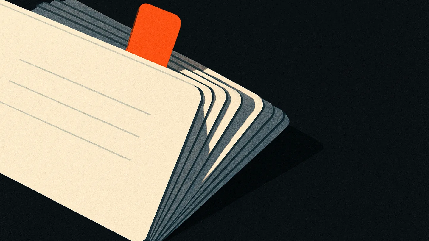 A fanned stack of index cards on black, one card pulled forward with a small ember-orange tab marking it.